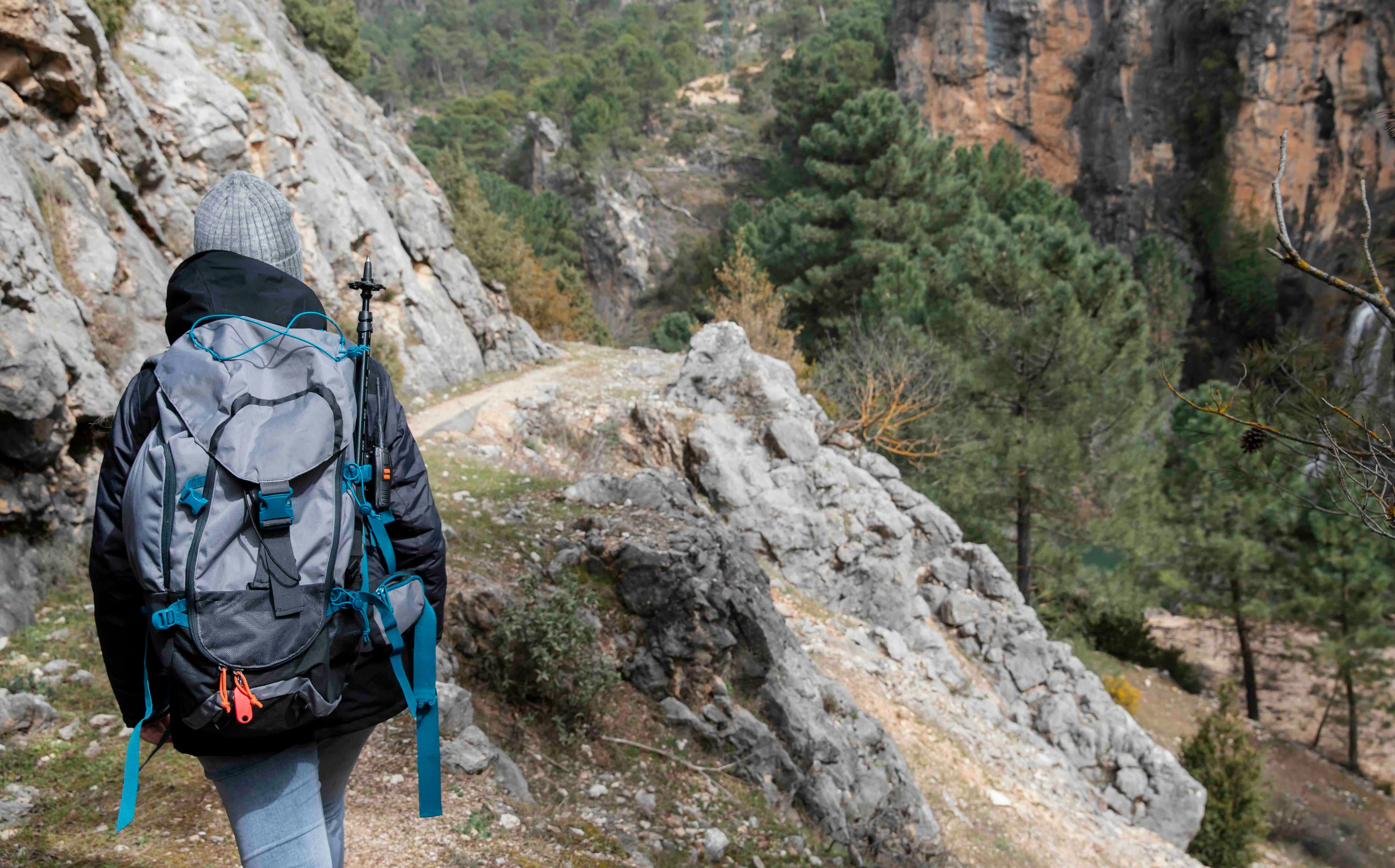 Chica caminando por la montaña de Andorra con una mochila llena de cosas preparada para acampar.
