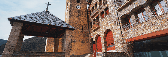 Ordino Andorra, parte de una iglesia románica en una plaza de Ordino centro con encanto, donde se ven arcos romanicos y un campanario con un reloj